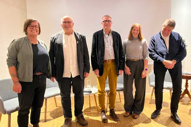 Die Teilnehmer der Podiumsdiskussion am 24.11.25 stehen zusammen und lächeln in die Kamera